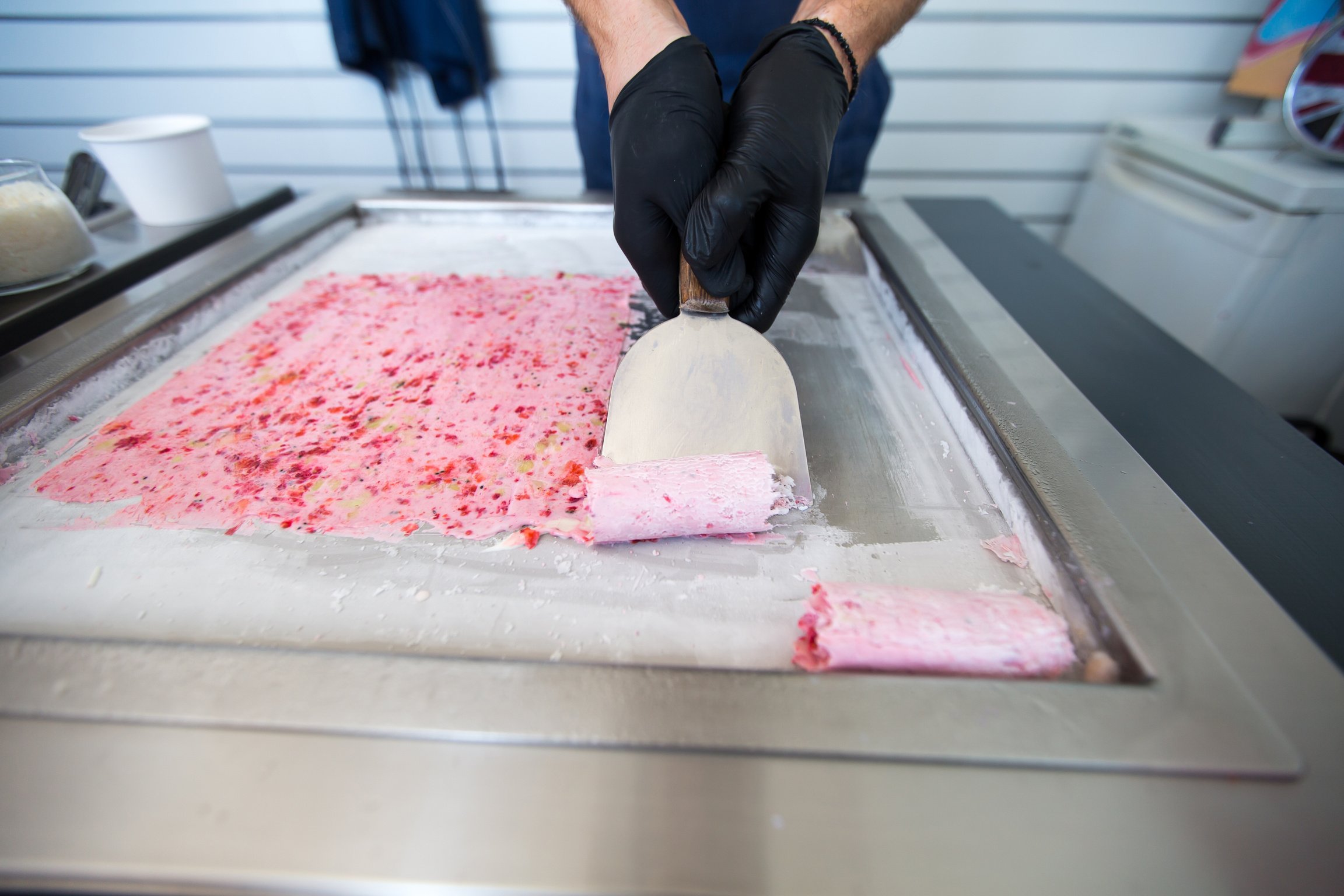 Stir-fried ice cream rolls at freeze pan. Rolled ice cream, hand made ice cream dessert. Fried ice cream machine with steel chilled pan.